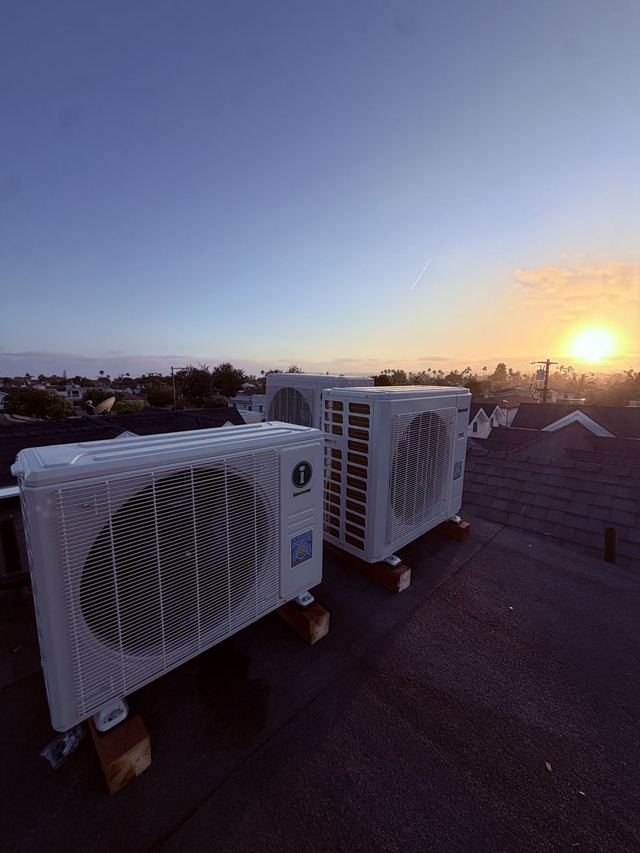 Mini split condensers on a rooftop at sunset